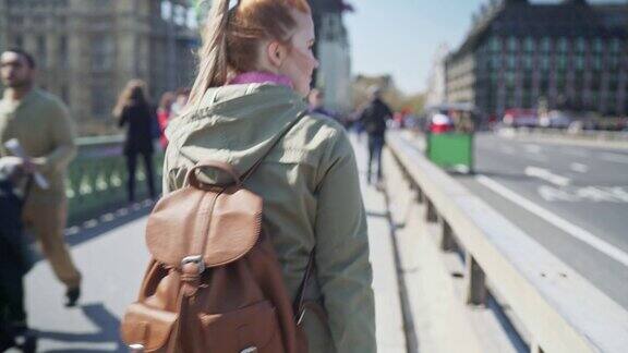 一个背着背包的女人在一个阳光明媚的日子里漫步在伦敦