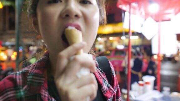 年轻迷人的亚洲女子在晚上的夜市享受华夫蛋筒草莓冰淇淋