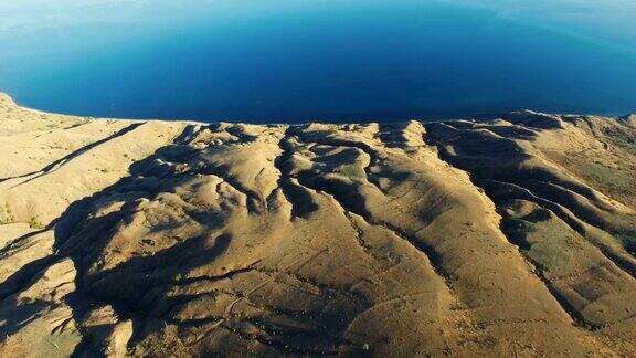AERIAL:沙漠山脉和蓝色海洋的未来主义景观