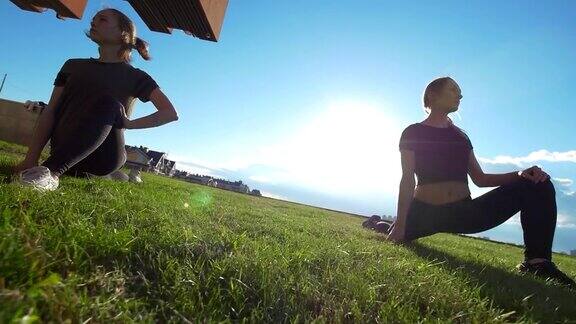 夏天日落时年轻的女杂技演员在草地上锻炼
