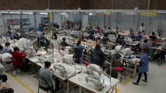 一群在服装厂工作的拉丁美洲员工每个人都在自己的工作岗位上戴着防护口罩