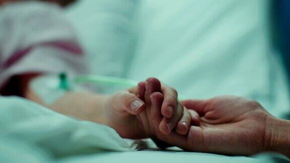 小孩躺在病床上睡觉妈妈握着她的手安慰