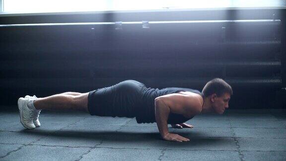 中景肖像肌肉强壮的男子做俯卧撑在地板上锻炼