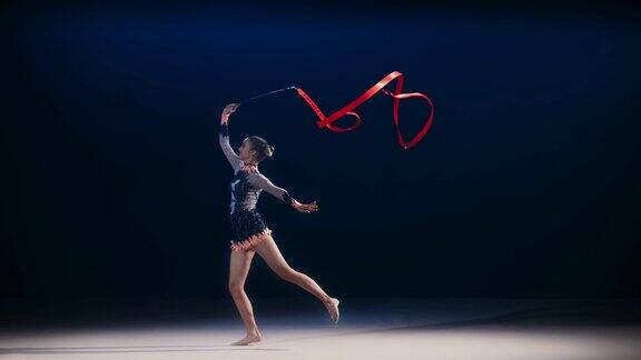 艺术体操运动员旋转红丝带并表演跳跃动作