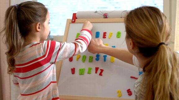 儿童早期发展一个年轻的女人教她的孩子字母