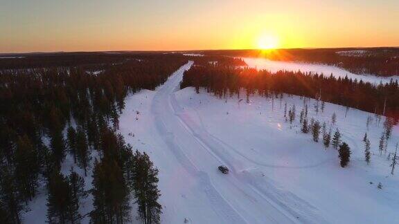 在金色的冬天的早晨空中汽车在空旷的结冰的道路上穿过白雪覆盖的森林