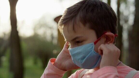 一个戴着医用口罩的人站在户外少年摘下面具