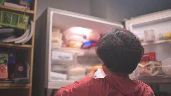 后视图亚洲华人老妇人晚上在厨房打开冰箱拿出冰冻的冰淇淋