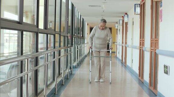 在走廊上用助行器走路的亚洲老妇人