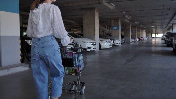 亚洲妇女购物拖着购物车到停车场