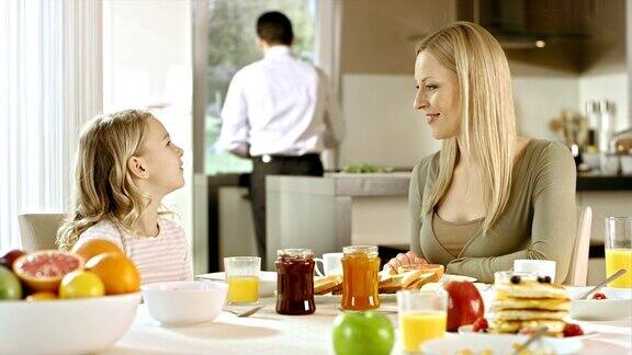 女孩在早餐桌上向她妈妈解释