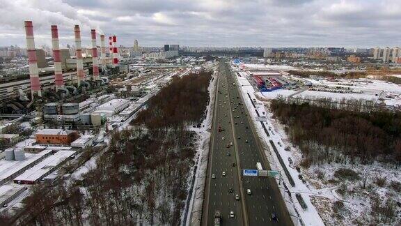 鸟瞰图飞行在高速公路与移动的汽车通过森林在寒冷的冬日