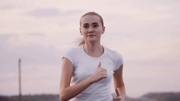 健康的生活方式穿着白色t恤的运动女孩在跑道上跑步那个女孩穿着运动服在城外的马路上跑步繁忙的交通背景