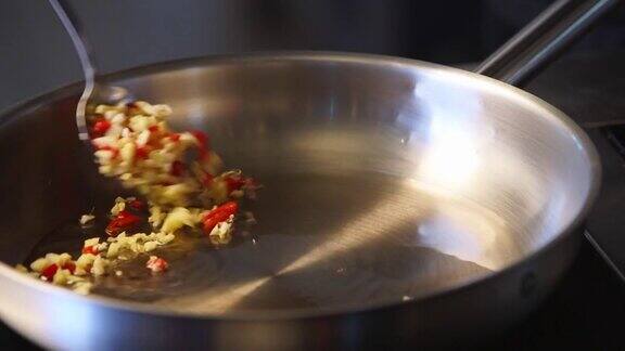 将油炸材料加入热锅中压碎的大蒜与百里香枝、菠菜和胡椒一起用慢动作拌入锅中