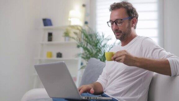 一名男子在客厅用笔记本电脑进行视频聊天