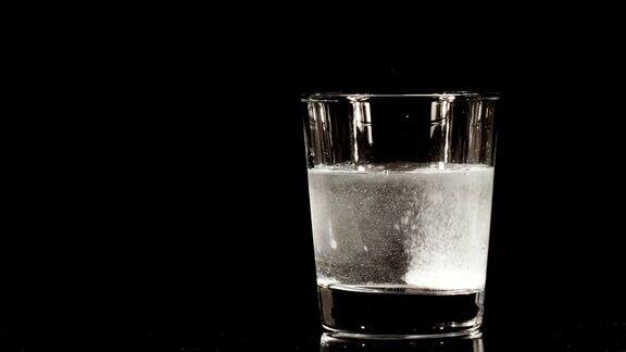 阿司匹林药丸落在装有水的黑色背景的玻璃杯里发泡片阿司匹林医学概念保健治疗慢动作
