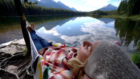 年轻女子在加拿大湖边的吊床上休息