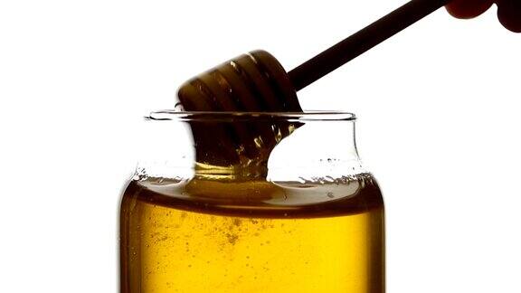 用木勺把玻璃罐里的蜂蜜拿起来孤立地放上白色慢动作收起来