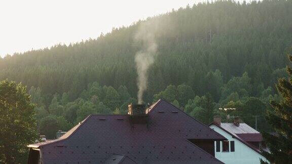 房子的屋顶有一个冒烟的烟囱在阳光下可以看到令人惊叹的山景在乡间森林里的小屋休息和放松