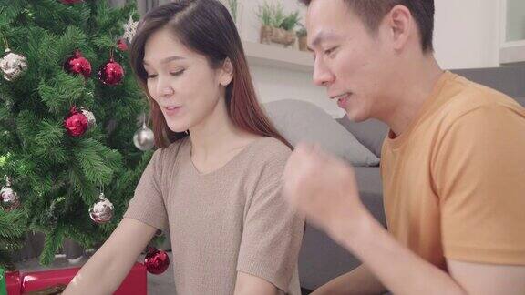 一亚洲夫妇在家里的客厅里给他的女朋友送圣诞礼物生活方式女人和男人快乐庆祝夏天圣诞节和新年