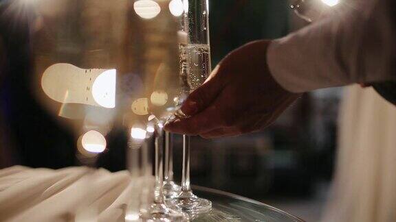 服务员正在倒香槟把香槟倒进玻璃杯里调酒师往杯子里倒香槟特写镜头香槟倒在玻璃杯里