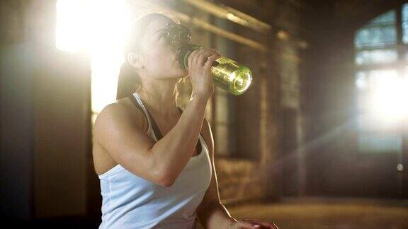 强壮的女运动员在她最喜欢的健身馆做完交叉健身训练后喝一瓶水