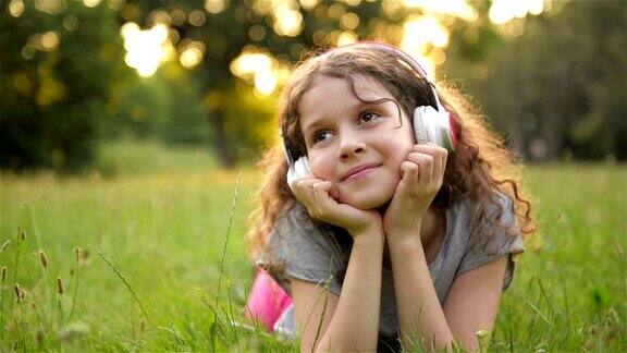 美丽的白人小女孩花时间在公共公园的肖像学生小孩有很多乐趣放松户外和听音乐与耳机