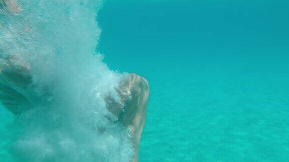 超级慢动作女子潜水在蓝绿色的海洋