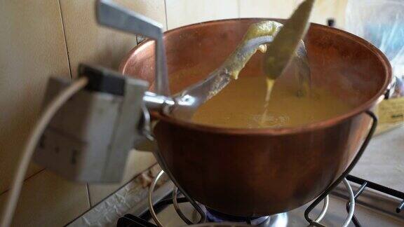 男子用木勺搅拌着滚烫的黄色玉米粥玉米粉粥差不多就可以吃了这是意大利北部乡村的传统菜肴美味的热玉米粥在铜锅上煮在火炉上