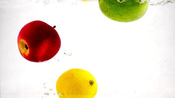 苹果、柠檬和橘子在慢镜头中冒着气泡掉进水里果实上孤立白色背景