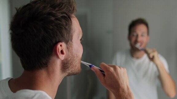 刷牙的男人用牙刷对着镜子看
