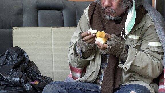 这个无家可归的人被施舍食物来帮助他的饥饿的慈善事业城市概念中无家可归者的问题