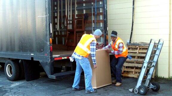 两名工人正在把大箱子装上卡车