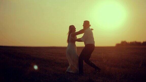 日落时分浪漫的情侣在草地上跳舞