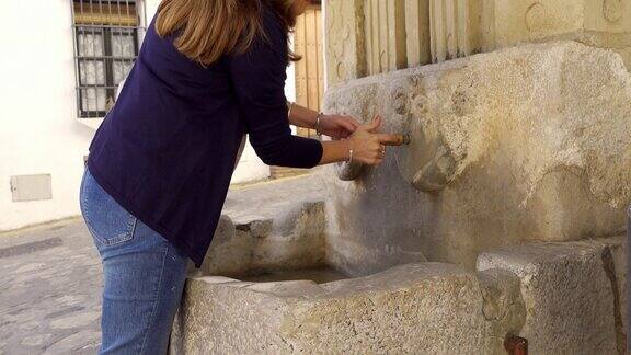 加的斯的格拉扎莱马一名妇女正在从一个古老的喷泉里喝水这个喷泉为行走的人提供新鲜的水