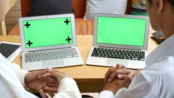 两人用绿屏笔记本电脑讨论