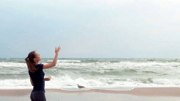 年轻快乐的女孩在海滩上喂海鸥慢镜头