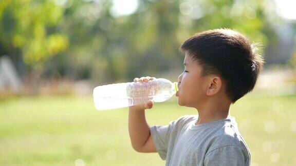 亚洲男孩在户外公园喝水