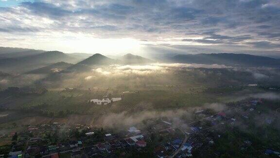 在雾天当太阳升起的时候无人机在山谷中乡村的城市景观
