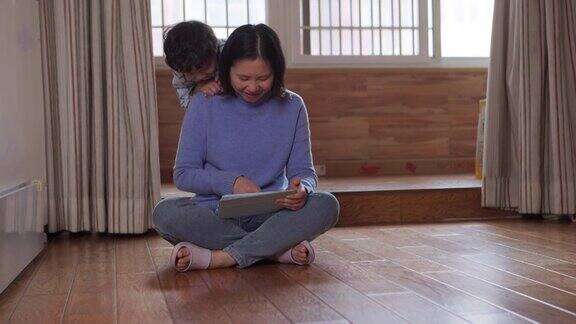 母亲和儿子在客厅用iPad玩游戏