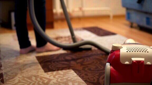 在客厅里用吸尘器清扫地毯的女人