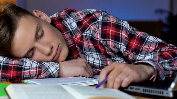 年轻人在课桌上打盹教育的无聊考试的疲劳