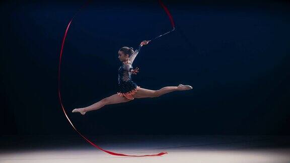 SLOMOLD艺术体操运动员在大范围旋转红丝带时做劈叉跳跃