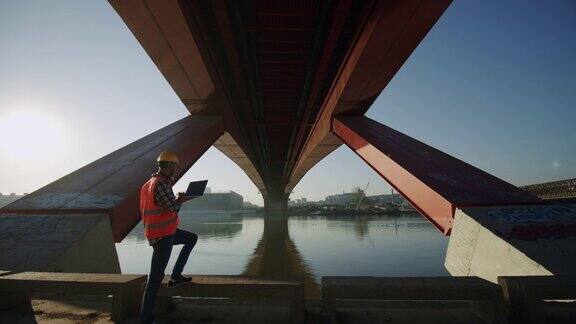 一名建筑师一边在电脑上打字一边检查建筑工地在户外