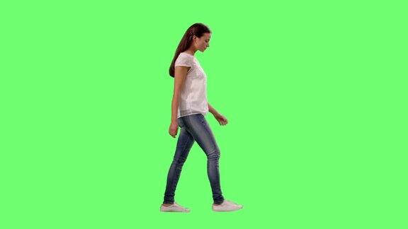 随意年轻的黑发女孩走在一个模型的绿色屏幕在背景