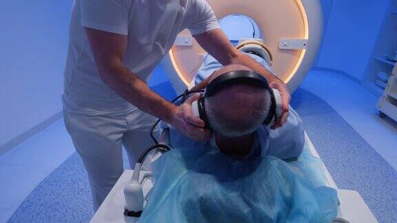 男护士在做核磁共振扫描前给病人准备耳机