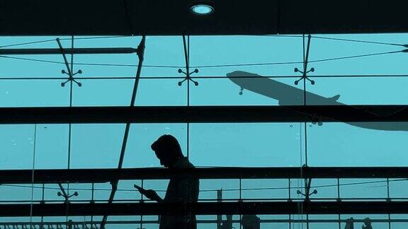 剪影游客和飞机在机场航站楼起飞