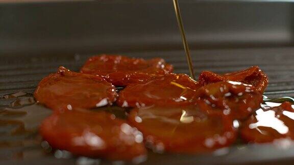 慢镜头:有机橄榄油洒在自家种植的晒干番茄上