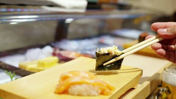 4K亚洲妇女用筷子在寿司板上吃日本食物寿司
