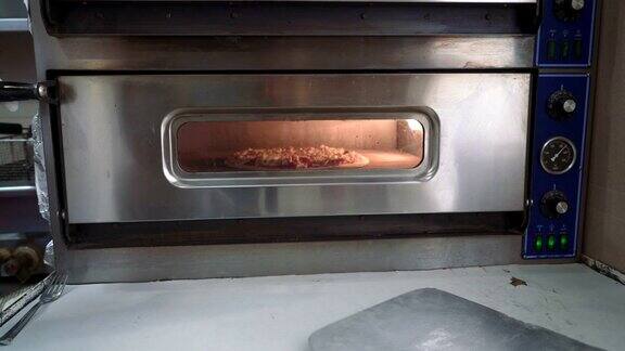 厨师把生披萨放进烤箱